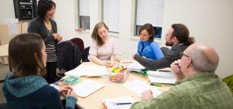 A group of adult students sit together at a round table.
