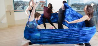 Five people pose within a large fabric wrap
