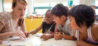 children playing cards and learning from their teacher