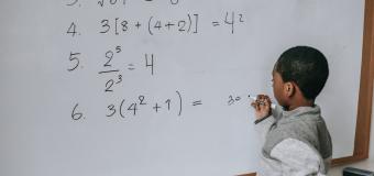 Small Black child doing a math problem at a whiteboard
