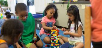 Group of children helping each other build a structure with colored blocks