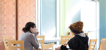 Two people speak at a table in Washburn dining hall.