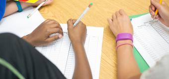 elementary school details of hands writing on a worksheet