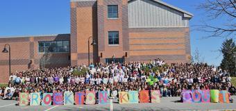 Student body at the George School in front of the school with sign Brockton Kids Count