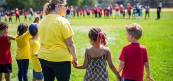 A long line of children and a teacher hold hands 