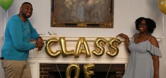 two people pose by the fireplace in Alumni Hall