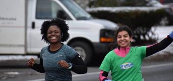 Imani Graham and Hanna Adams (who is on the right) smile and Hannah waves during a run.
