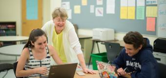 teacher helping a student on the computer