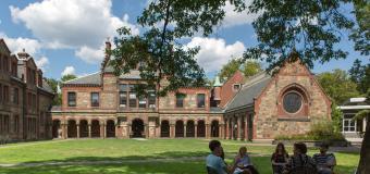 Students sit in chairs in a circle having a class discussion on Lesley's lawn.