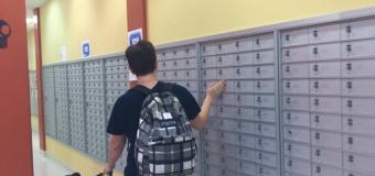 student with service dog walking by student mailboxes