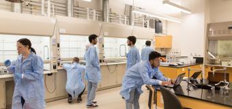 Landscape view of the lab with students working in their lab coats.