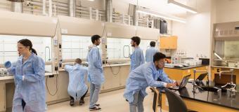 Landscape view of the lab with students working in their lab coats.
