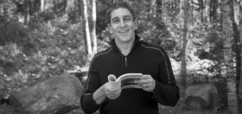 Richard Blanco looks at the camera and holds a book.
