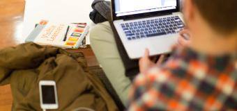 Student studying with computer and book and iPhone