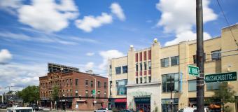 Buildings on a busy city street with blue sky and clouds