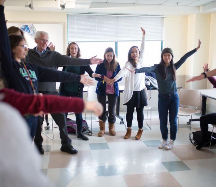 Professor Bill Mitchell Leading a Threshold Class surrounded by students with their arms outstretched
