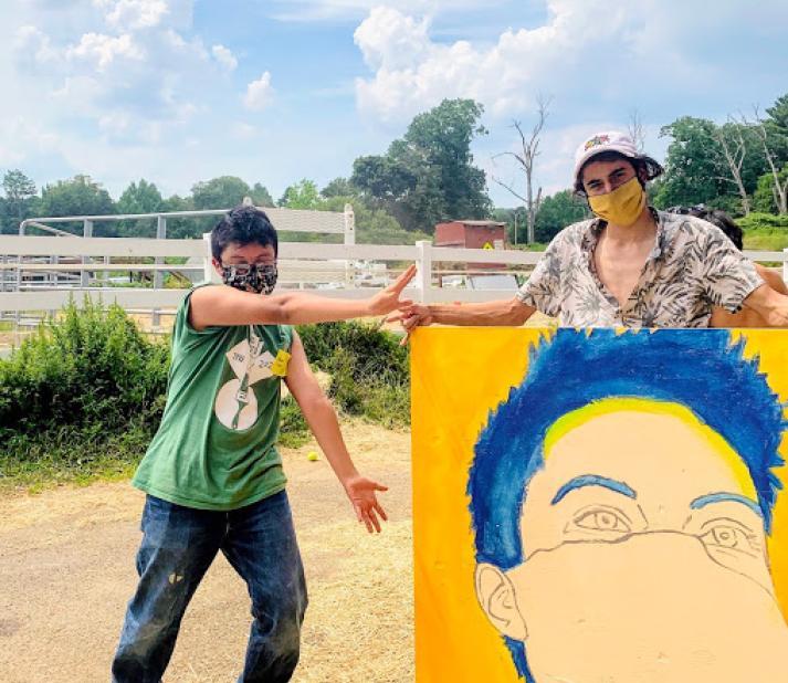 Portrait in progress of Jon Lopez-Wilen. Stands with a student, both are masked.