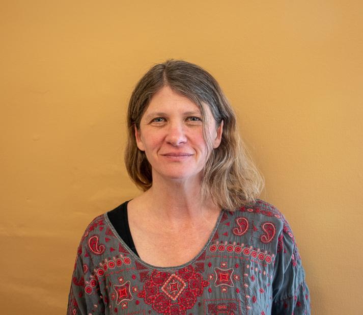 Sara Levine headshot against mustard colored wall.