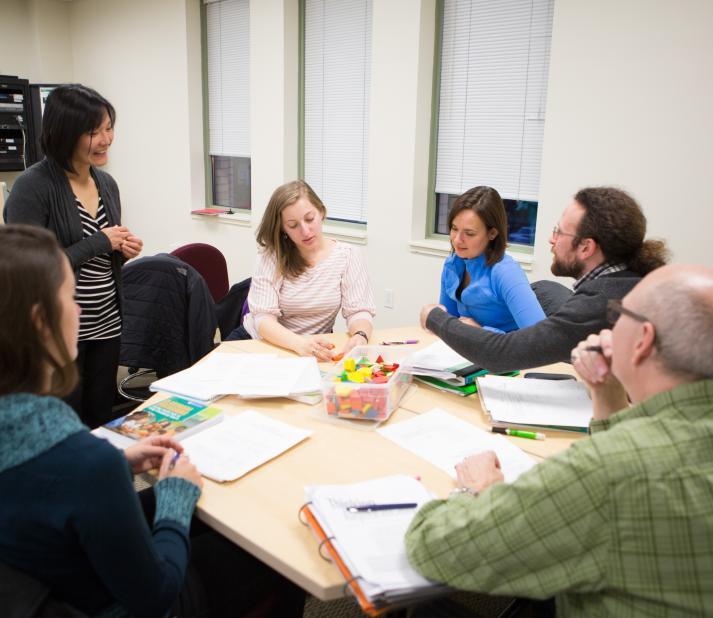 A group of adult students sit together at a round table.