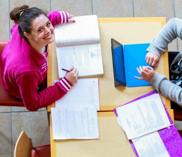 Two female students smiling while at work