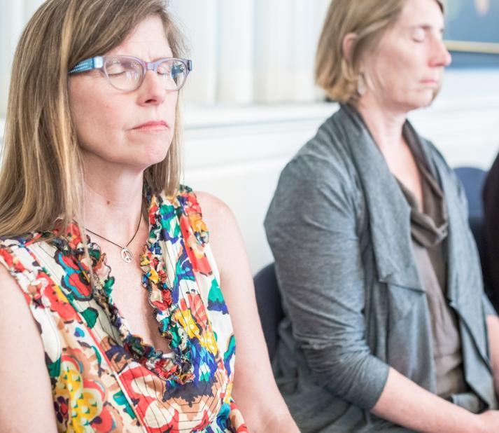 Three students sit quietly in meditation with their eyes closed.