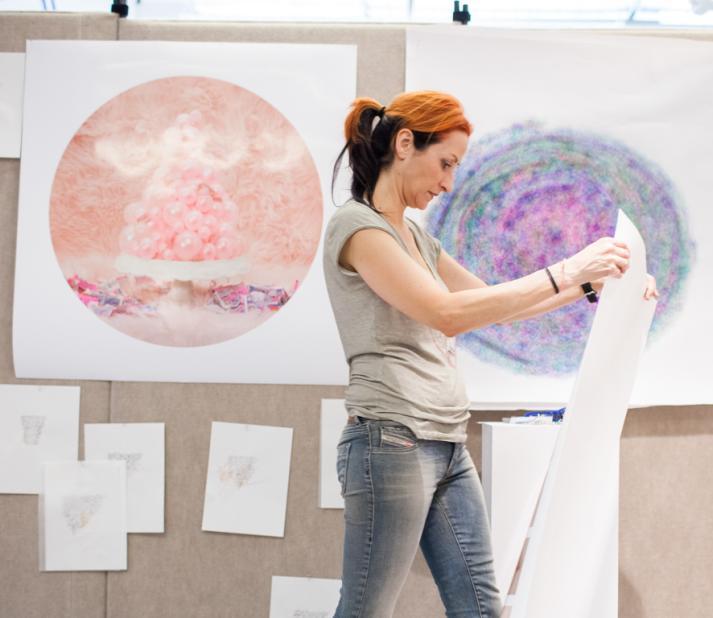 Artist holds up one of her pieces of art.