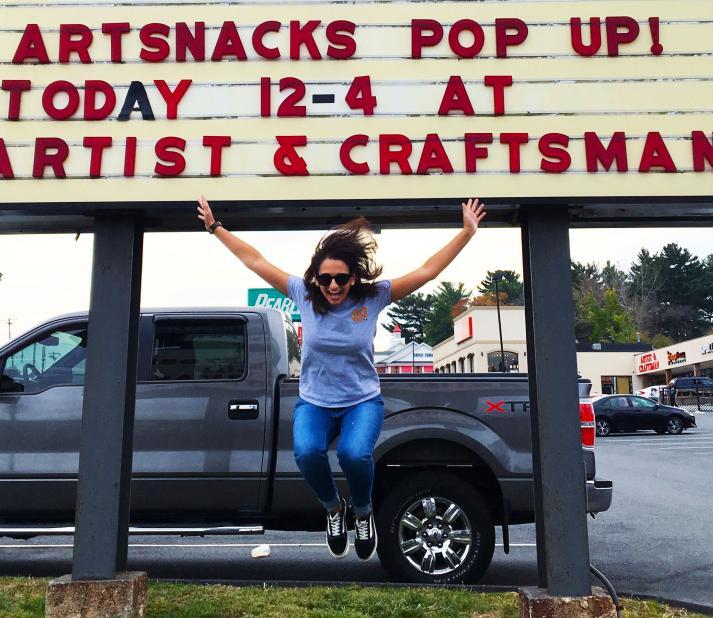 Sarah jumps for joy infront of store sign on side of road
