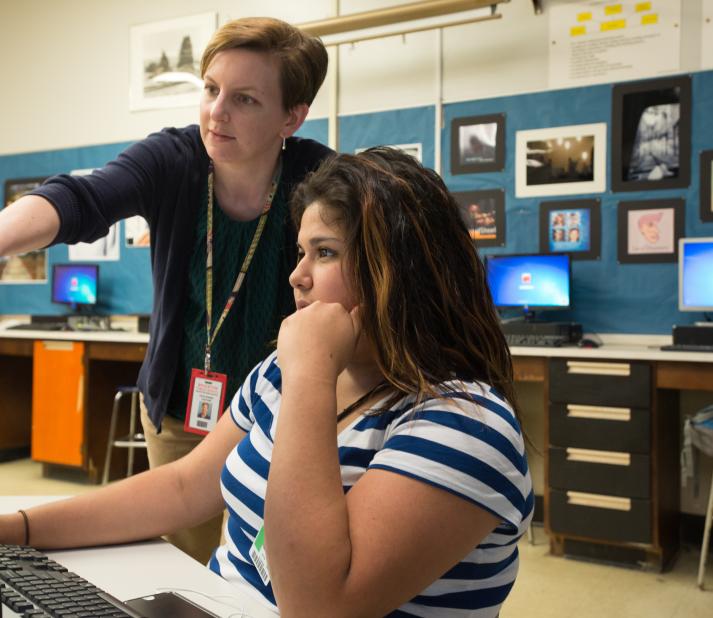 Teacher teaching a high school student at a computer