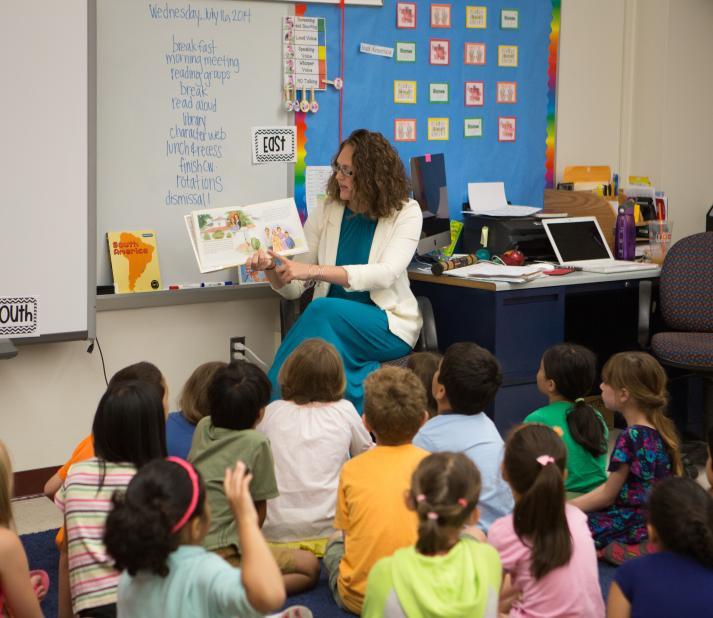 Teacher reading to a group of small children 