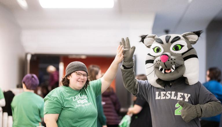 Lesley student high fives to Lesley Lynx mascot