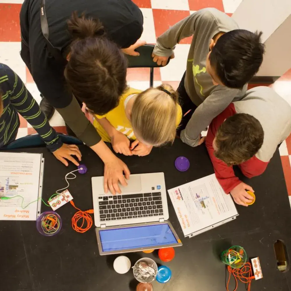 Students crowding around a computer, finalizing their coding project