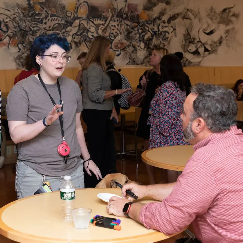 Justin Richmond sits at a table and speaks with Lesley students