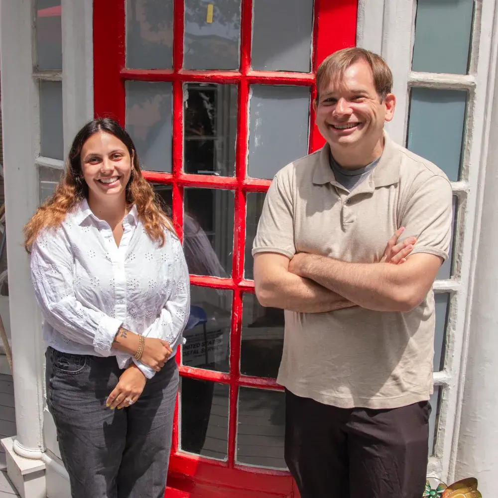 two people standing in front of red door with the address "70"
