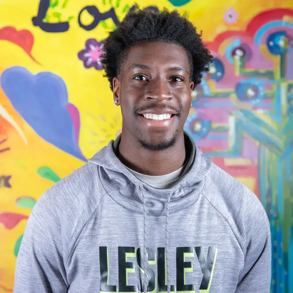 student in front of mural