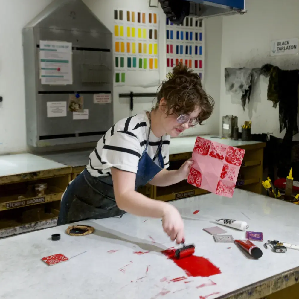Person spreading ink on a table in an art studio