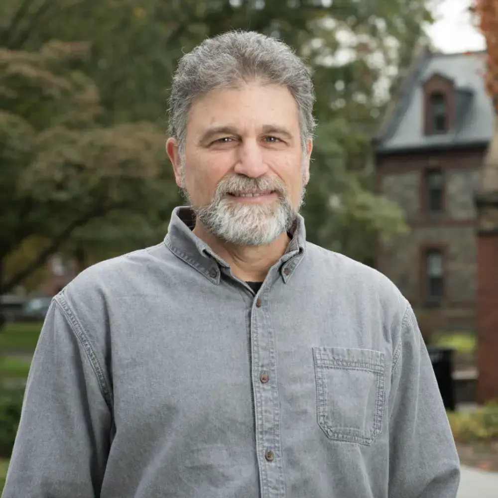 Mitchell smiling outside wearing grey button-up