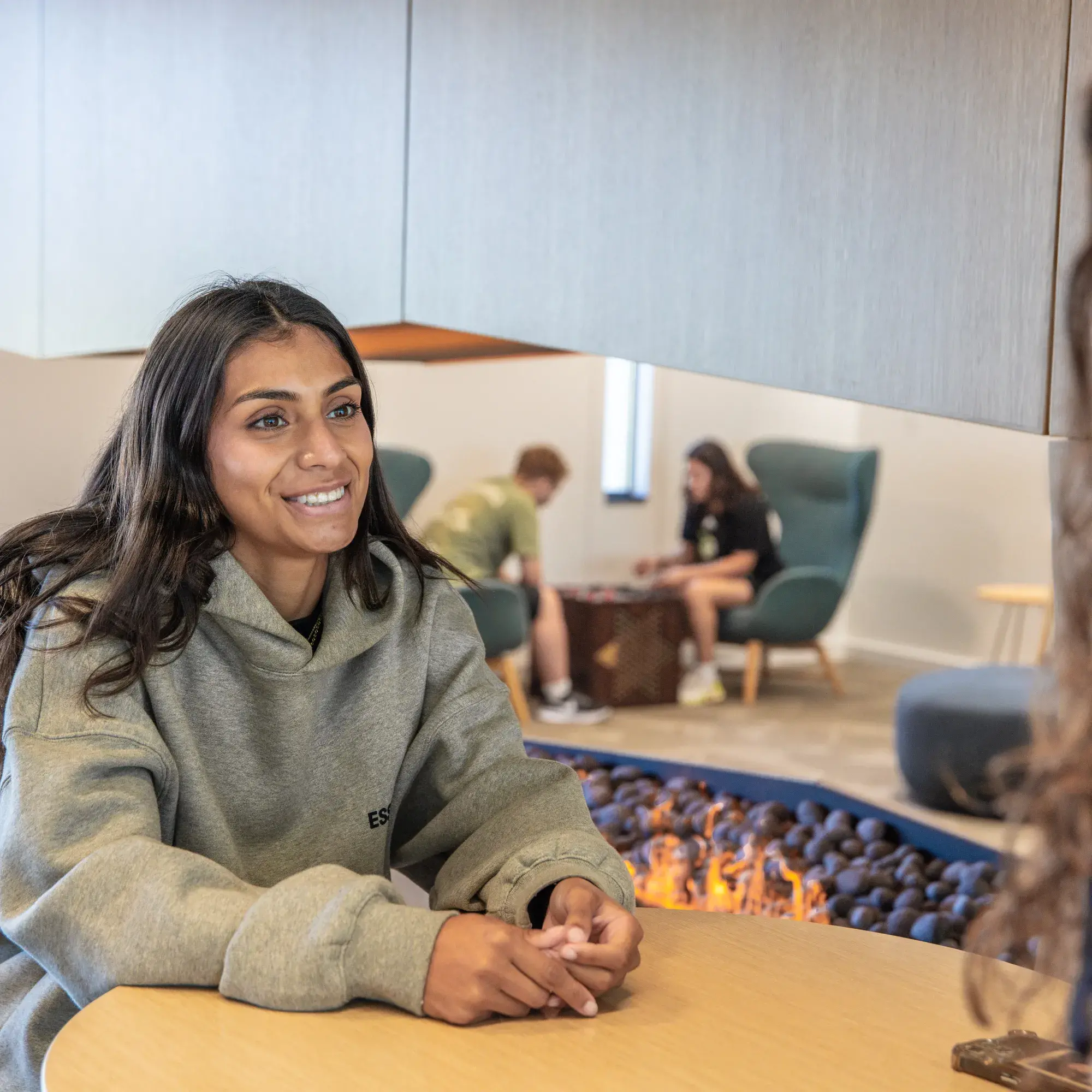 Student seated at a small round table smiling