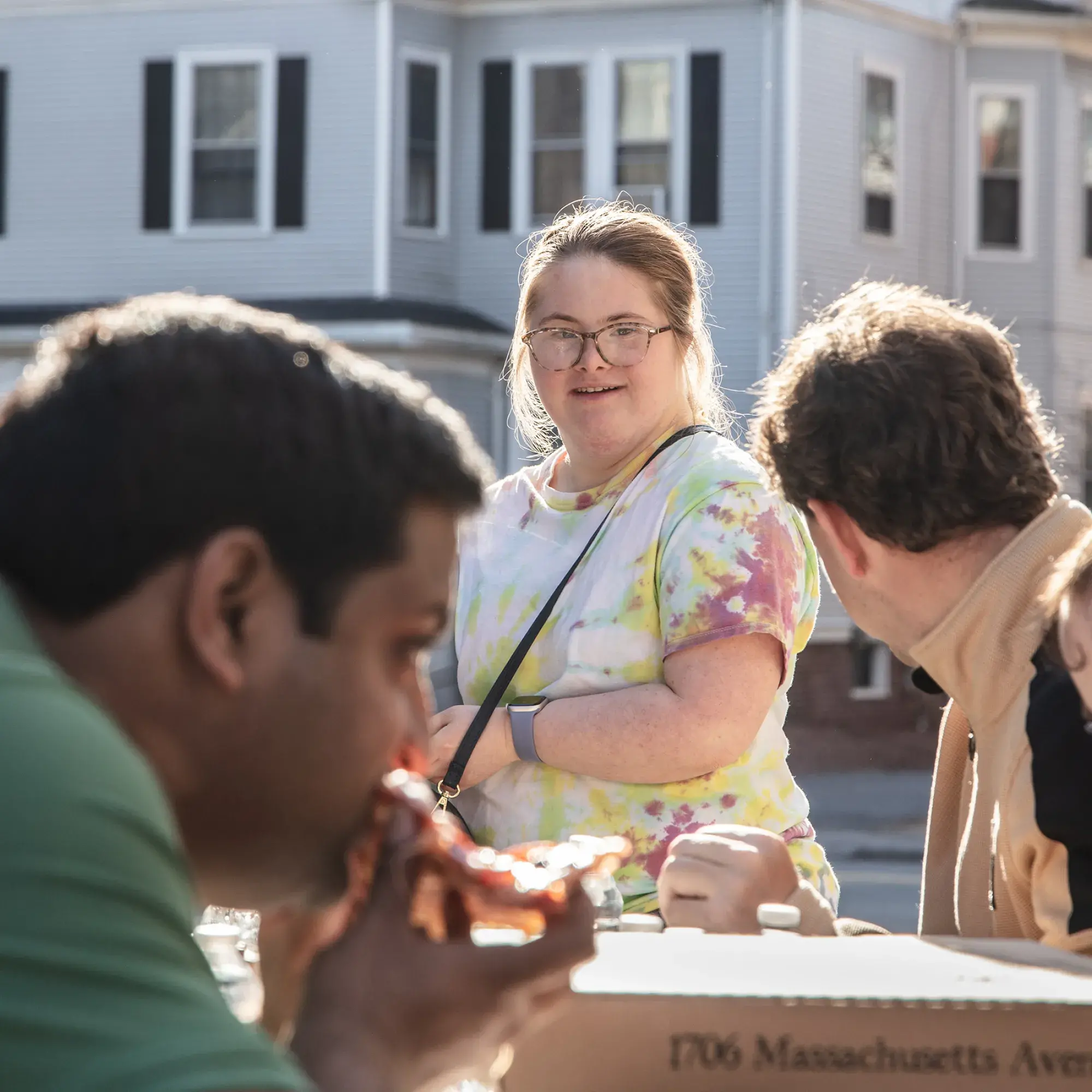 Students sitting around an outdoor table with pizza