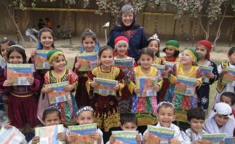 Professor Louise Pascale and a group of Afghan children with their songbooks