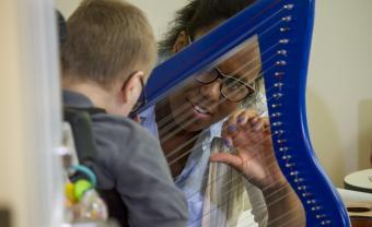 Woman looks through a small harp at a child