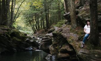 Photographer Kelly Burgess stands by a shady green Vermont swimming hole.