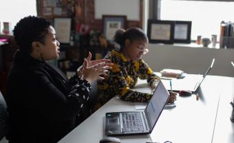 Myisha Rodrigues in an office talking with colleagues at a conference table