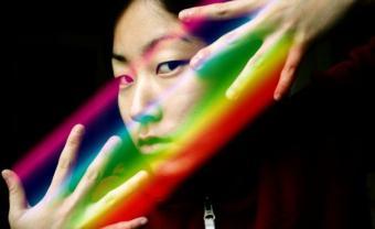 Artistic photo of Noel King with hands around face and prism over her fingers