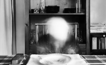 Black and white photo of someone at a dinner table who has been ghosted out