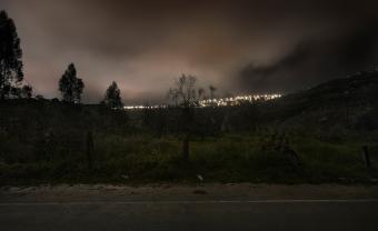 photograph of dark field with city lights in valley below