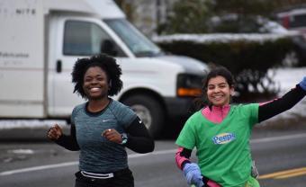 Imani Graham and Hanna Adams (who is on the right) smile and Hannah waves during a run.