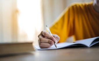 A person's hand on a desk, writing