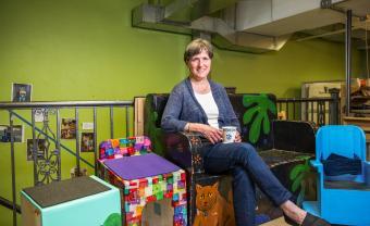 Woman sitting on a colorful chair in a classroom.