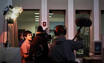 students on set with boom mic, camera, and spotlights
