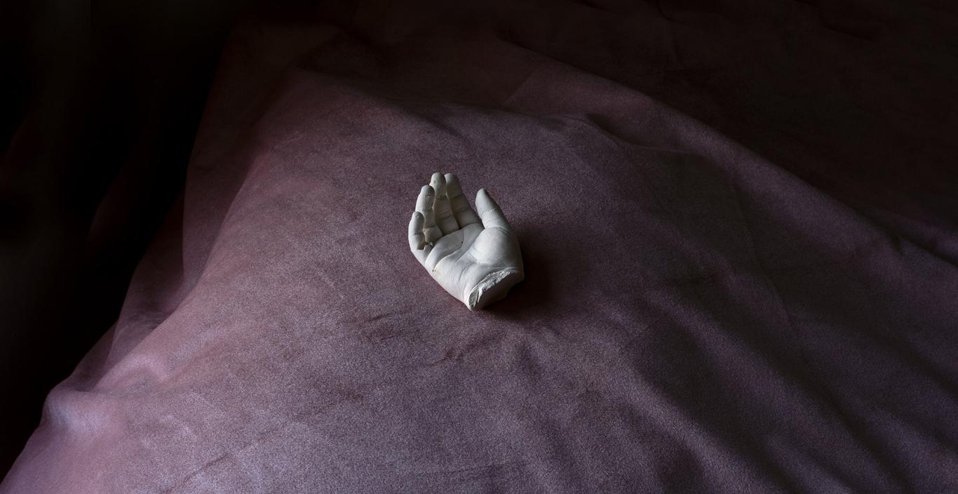 Artwork by Ahdraya Parlato, a cast of a hand face-up on purple fabric.